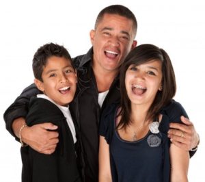 smiling man with arms around boy and girl