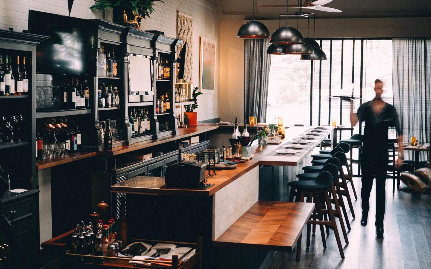 modern restaurant with waiter holding tray in front of bar while walking forward